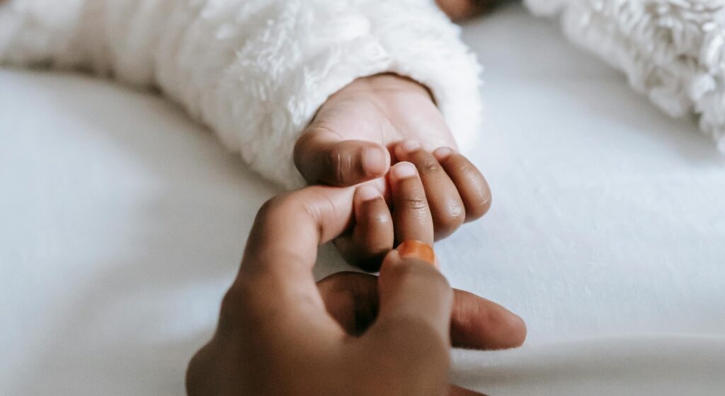 an adult holding a baby's hand representing is addiction hereditary.