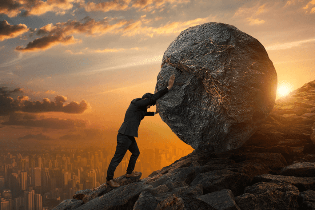 A man pushing a rock up a hill alone, showing the need to ask for help during addiction