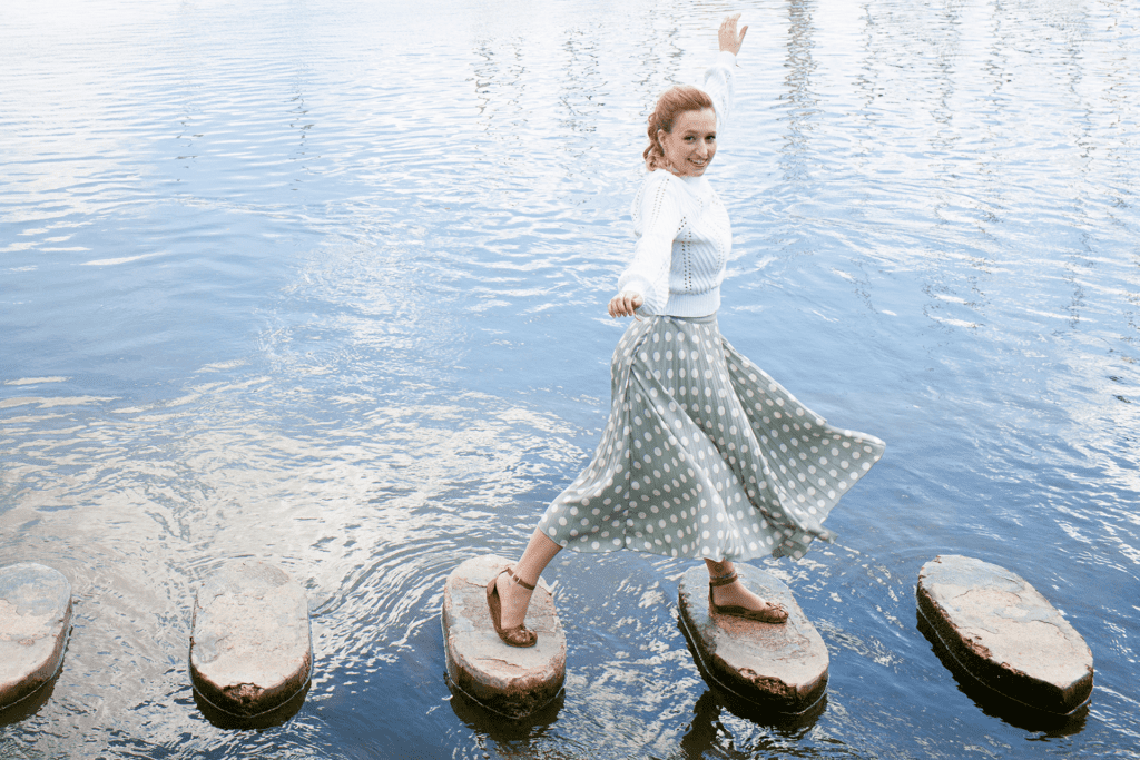 A woman walks across stone steps through a body of water, depicting setting objectives for alcohol addiction treatment