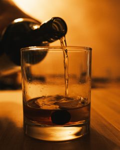 An image of a someone pouring a glass of whiskey, depicting the question: am I a functioning alcoholic?