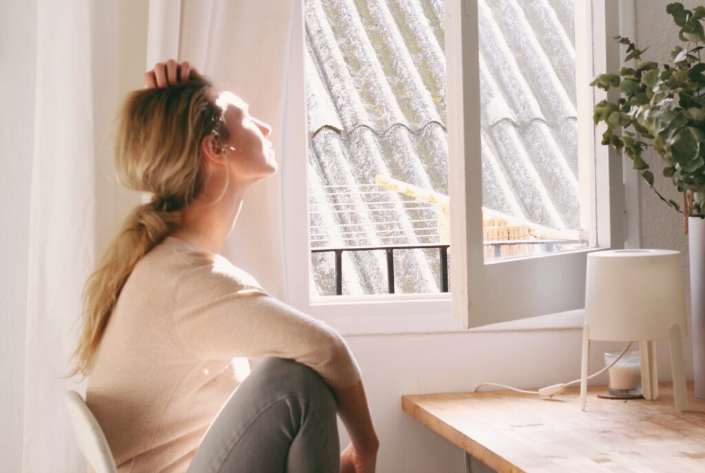 An image of a woman looking out a window to represent the question: what is GHB?