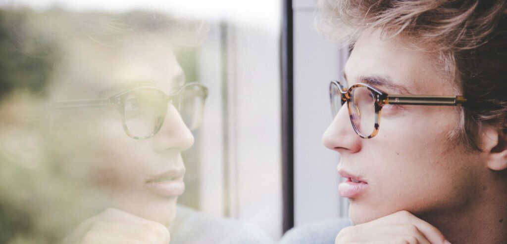 A man stares out a window to represent prescription drug detox process