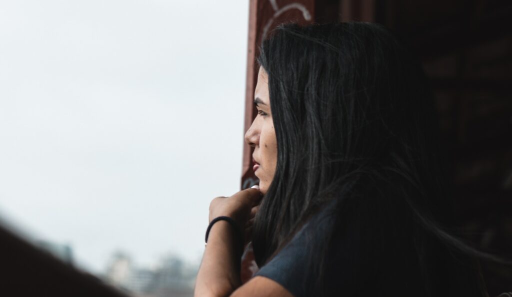 A woman looks out a widow to represent the question: is alcohol a stimulant?.
