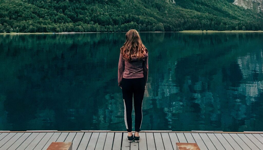 A woman looks out at a lake to represent wondering, "What Are the Long-Term Effects of Alcohol Abuse?".