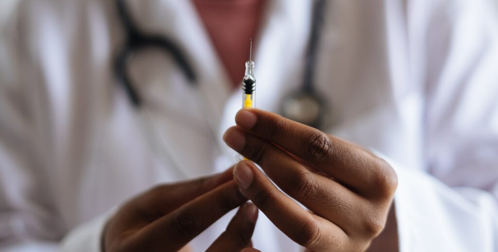 An image of a medical professional holding a shot to represent the question: "how does the vivitrol shot work?".