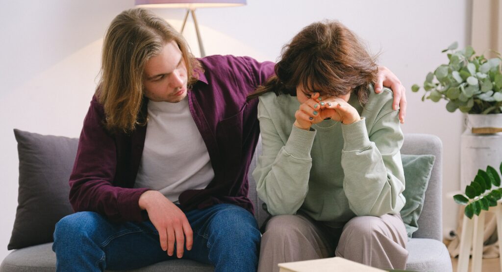 A man has his arm around a sad woman to represent oxycodone and alcohol treatment.