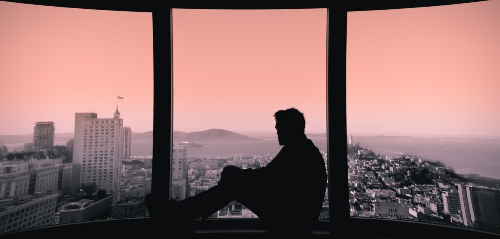 Man looks out window to represent adderall addiction signs