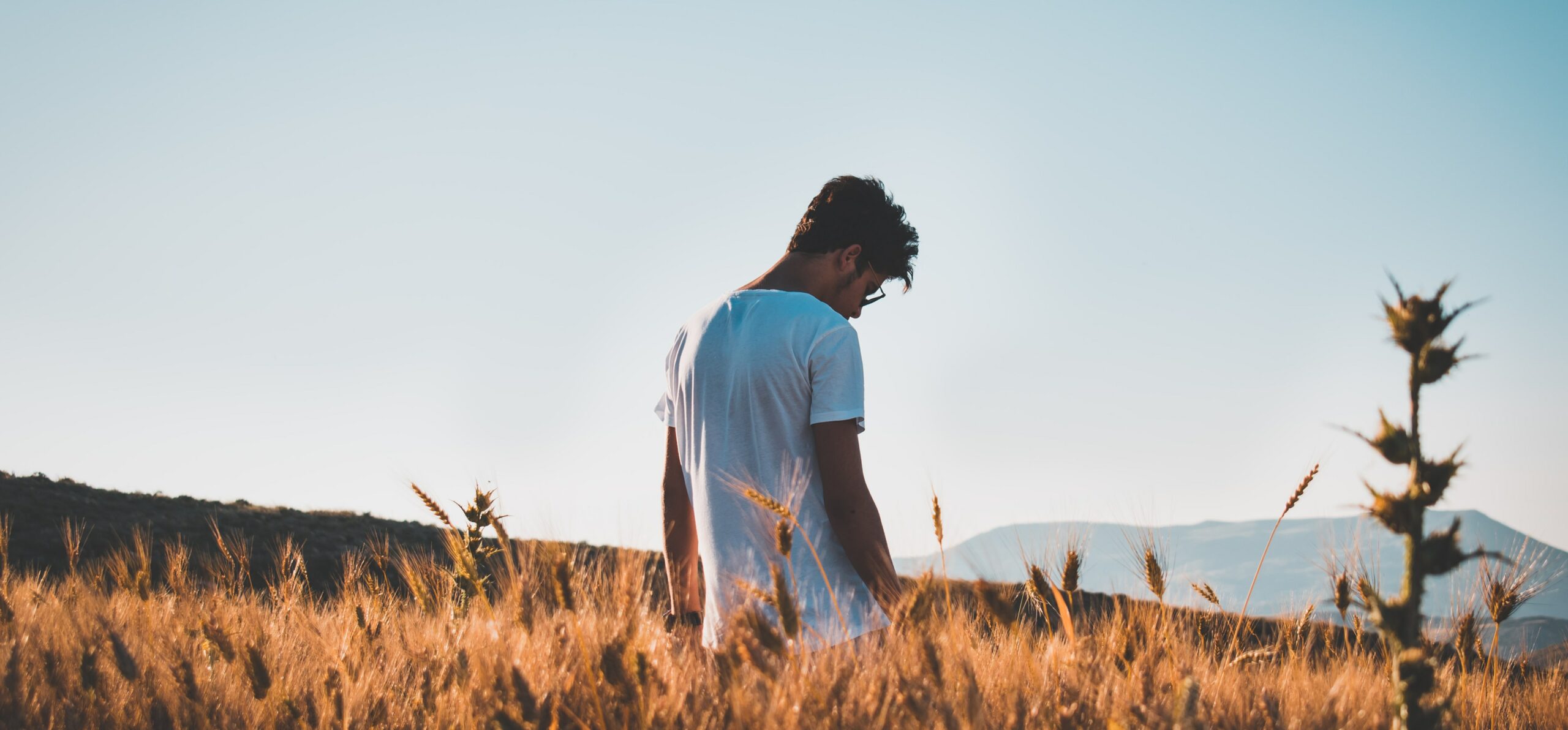 A man stands in a field looking down to represent what is addictive personality disorder.