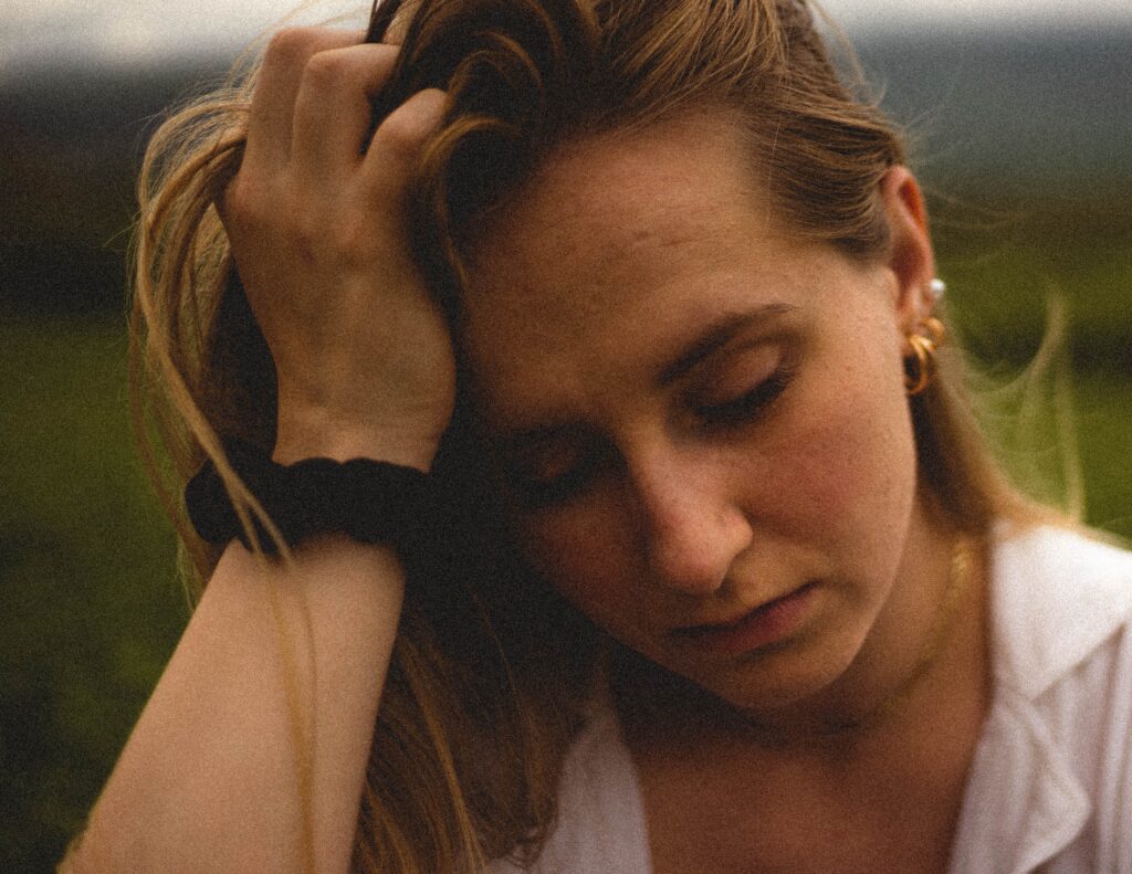 A woman has her hand on her head to represent opioid addiction symptoms.