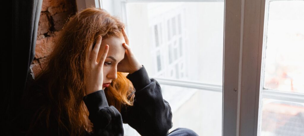 A woman sits with her hands on her head to represent clonazepam withdrawal symptoms