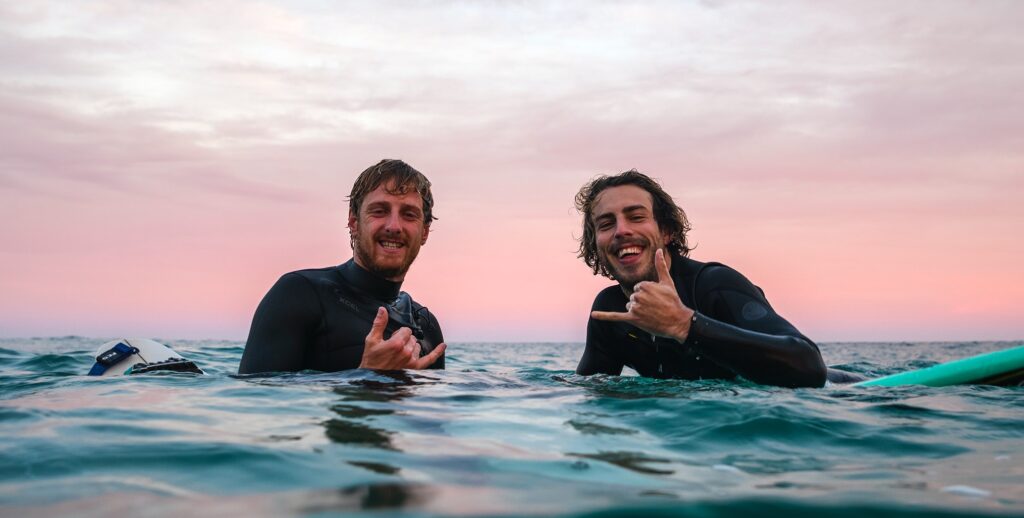 Two people are on surfboards to represent the benefits of surfing on mental health.