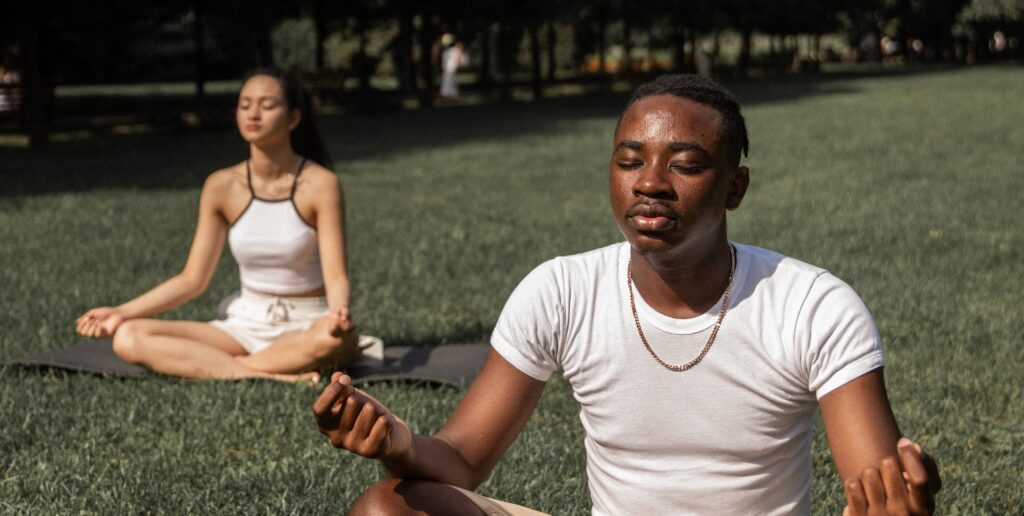 Two people practice yoga to represent yoga for addiction.