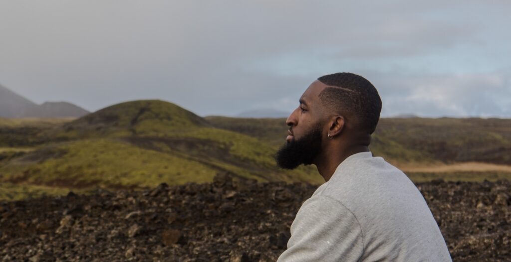 a man looks out at scenery representing heroin addiction treatment benefits.