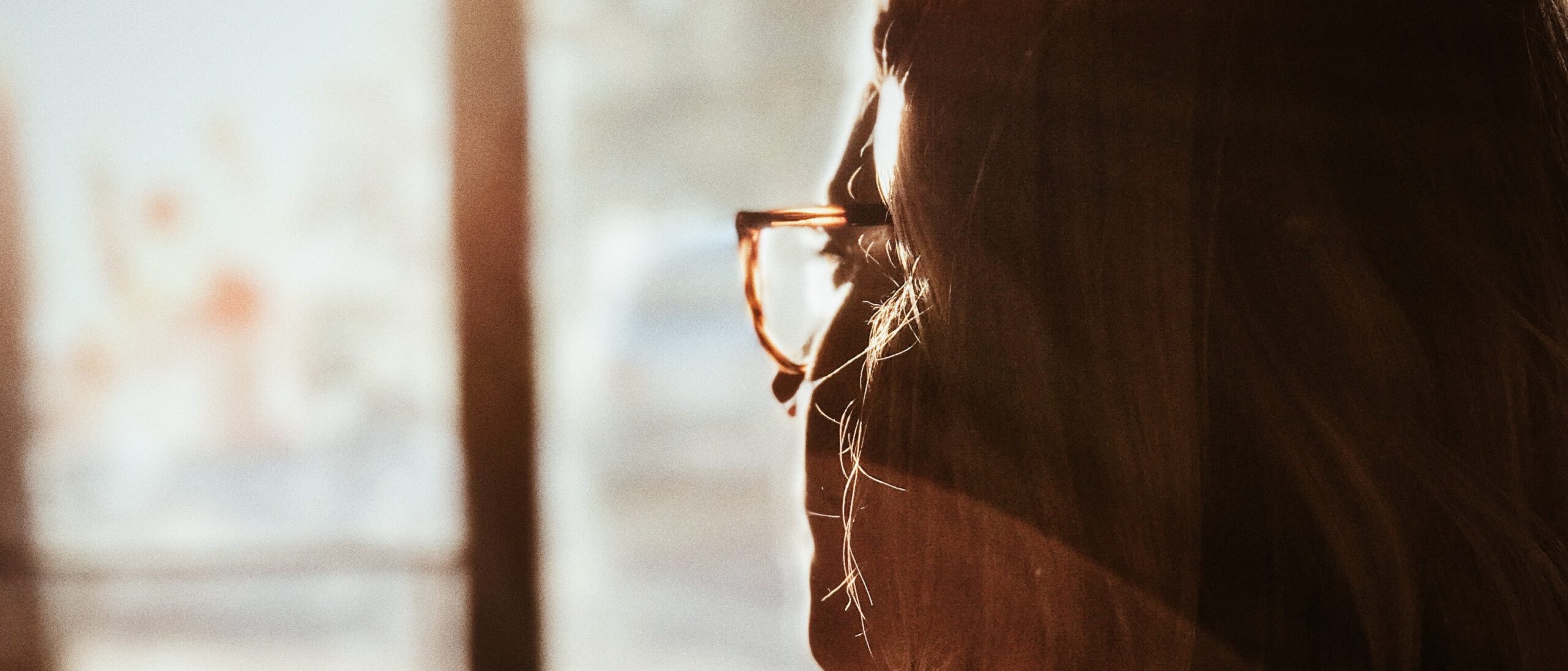 Woman looks out a window representing Alcohol and zoloft .