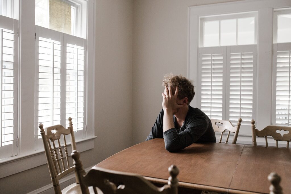 An image of a man sitting at a table struggling with some of the short term effects of barbiturates