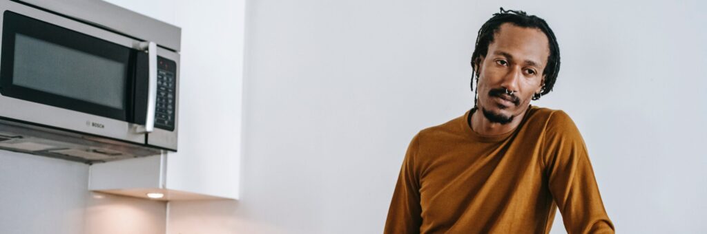 A man leaning on the kitchen counter in deep thought about GHB addiction and treatment
