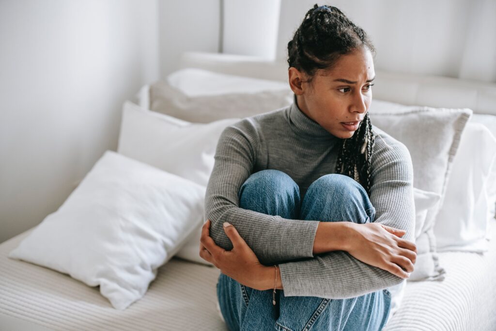 A woman sitting on the bed in distress, depicting what is meloxicam used for