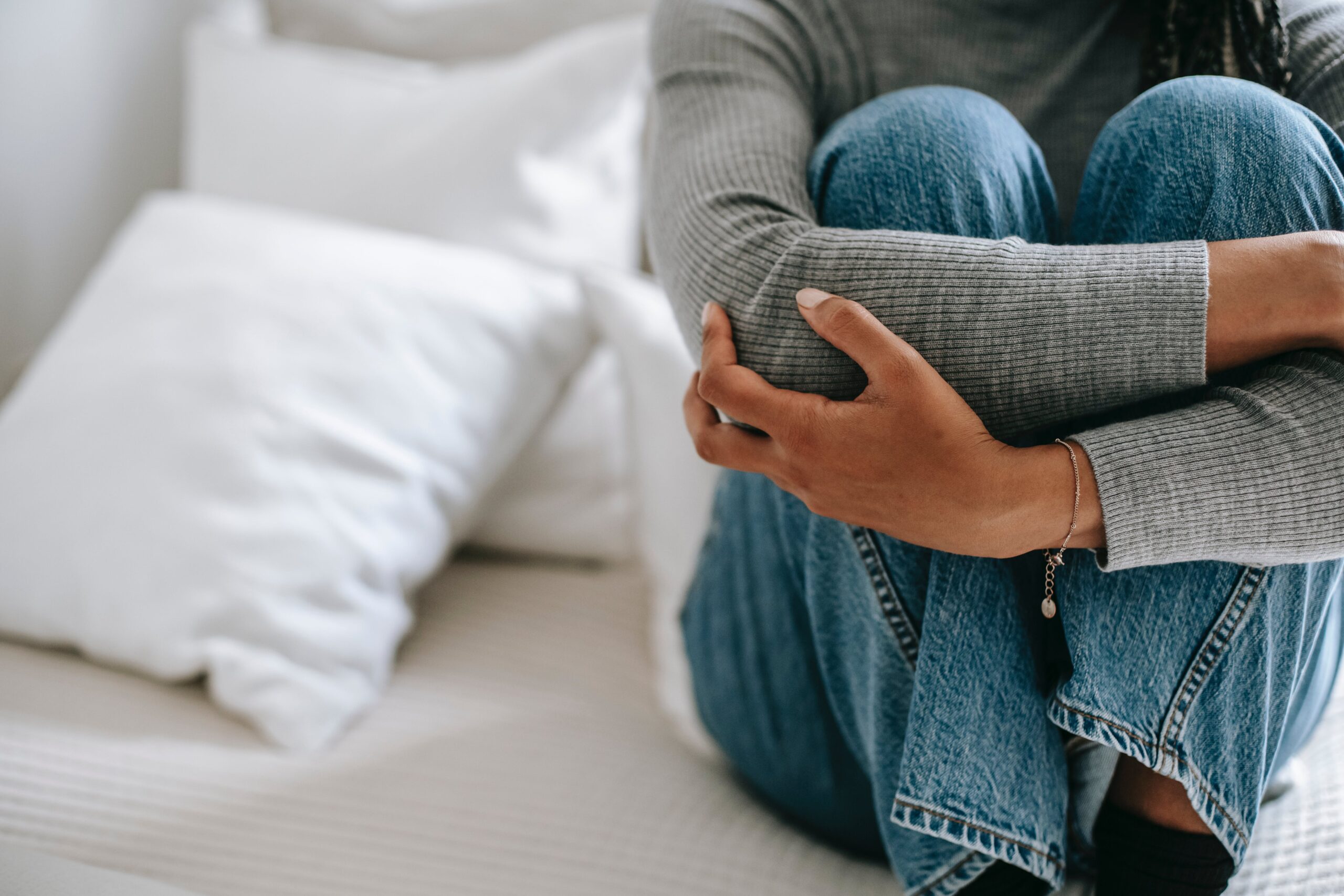 Somebody sits upright on their bed, representing physical signs of meth use