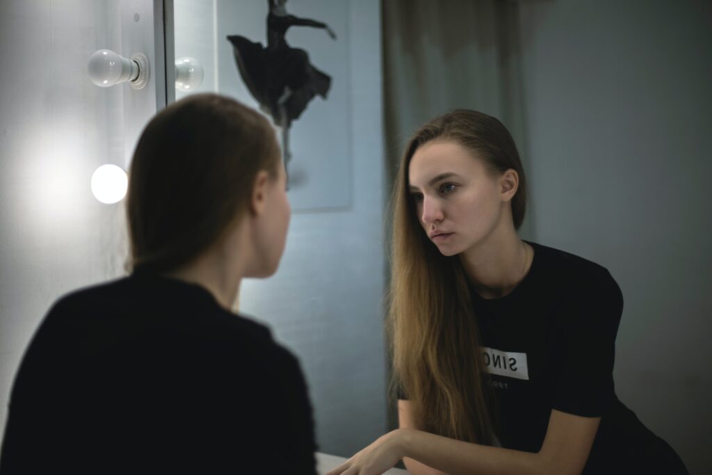 A woman looks in the mirror in thought after experiencing some of the Long term side effects of Xanax