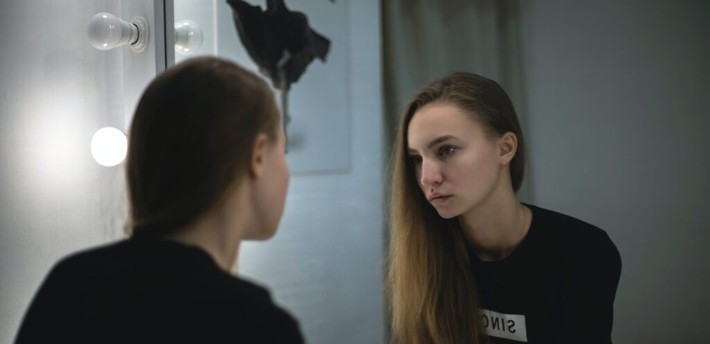 A woman looks in the mirror in thought representing signs of meth use
