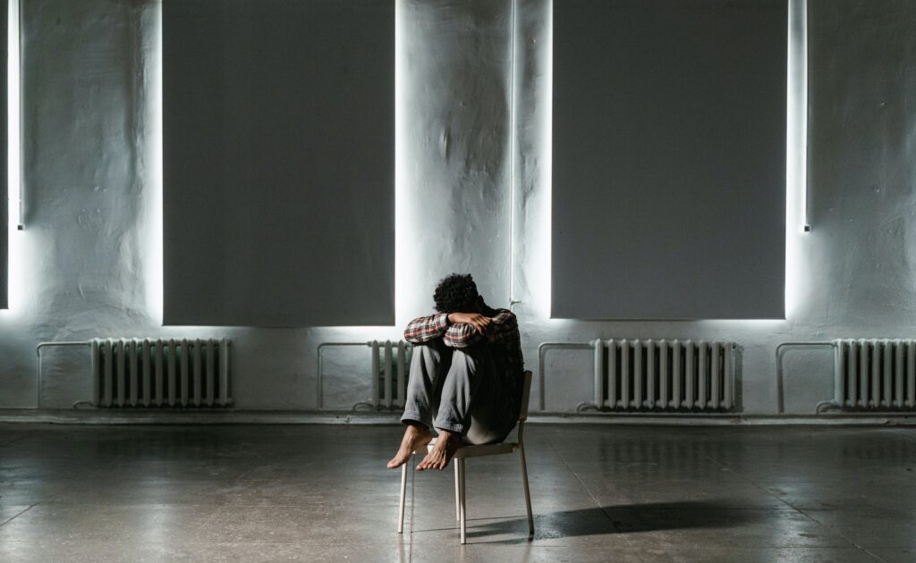 A man in a room alone, sitting n a chair troubled after learning about Benzo overdose symptoms