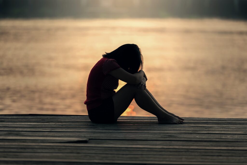 Image of a woman sitting on a dock by herself to represent withdrawal timeline for heroin detox