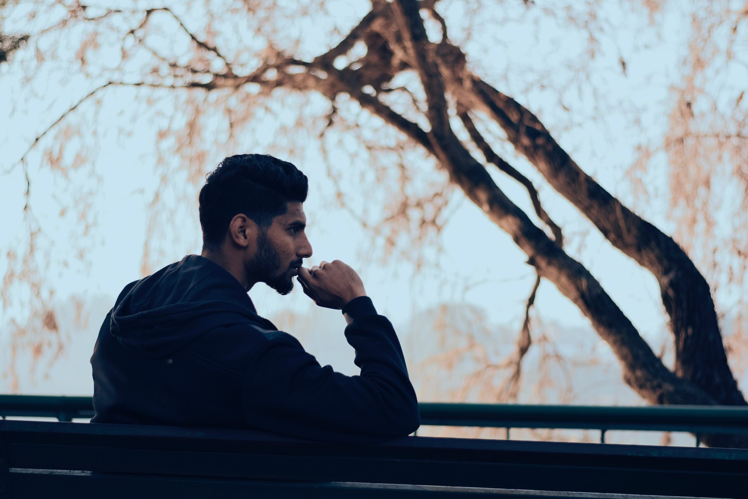A man sits on a park bench wondering, "why are drugs laced with fentanyl?"