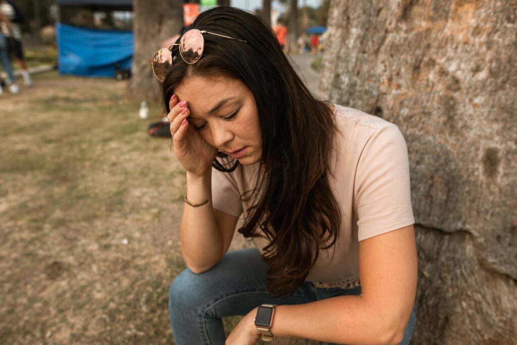 A woman holding her hand to her head, showing Drug induced psychosis symptoms