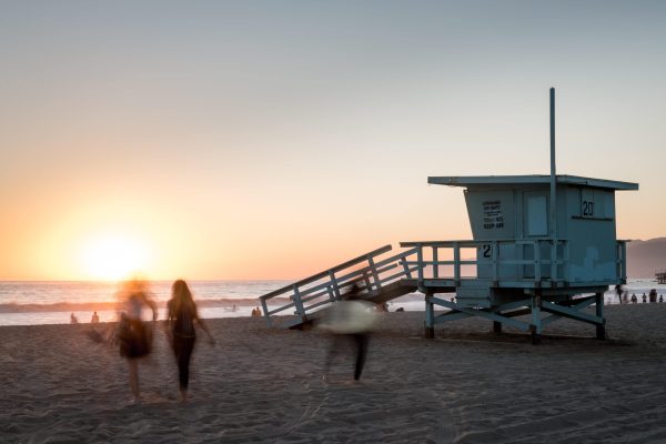 people walk on the beach at sunset representing luxury rehab in california